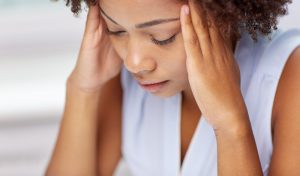 people, emotions, stress and health care concept - unhappy african american young woman touching her head and suffering from headache